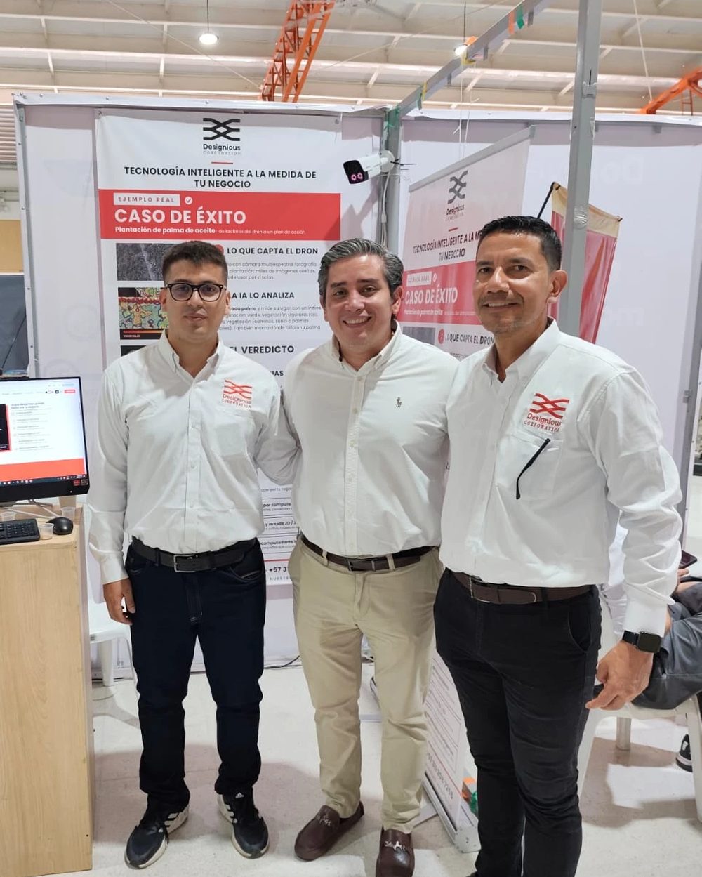 Tres personas frente al stand de Designious Corporation durante la feria